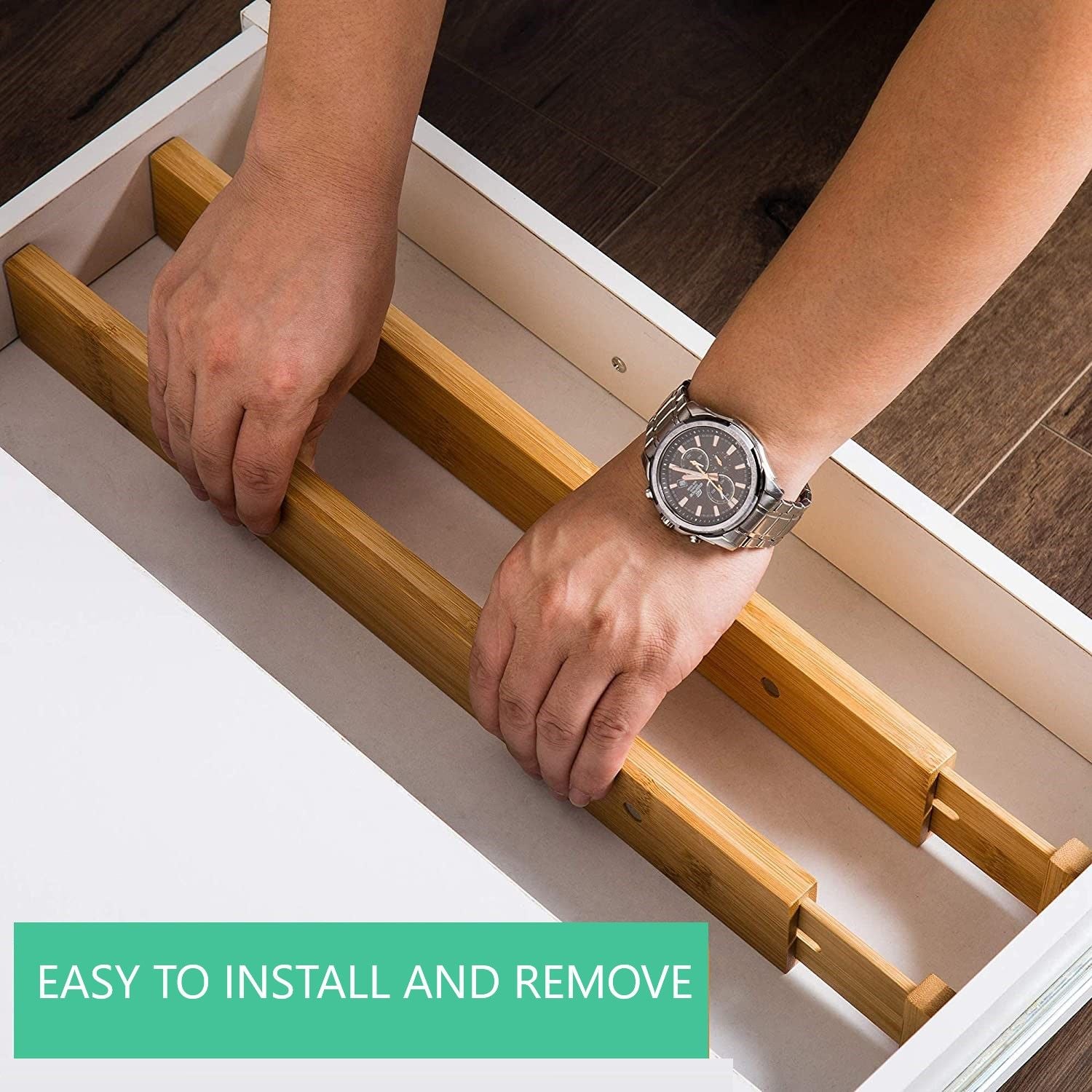 Adjustable bamboo drawer divider with black grips, being placed inside a white drawer