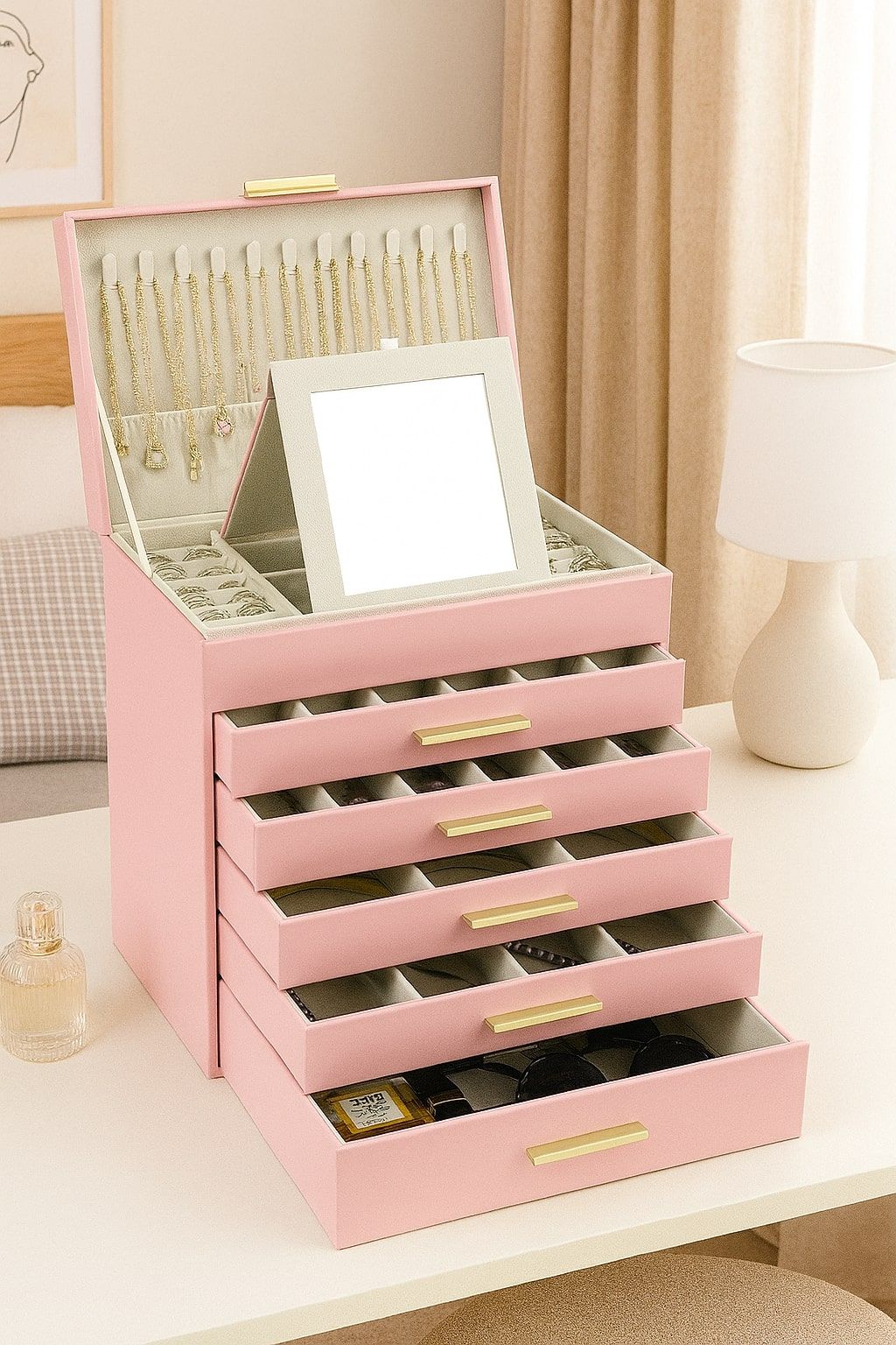 Pink jewelry organizer box with mirror and stacked drawers, open compartments