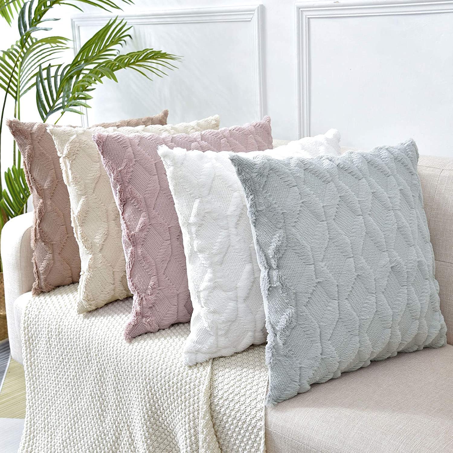 Set of textured pillow covers in pale pink, white, and one light color with fringe