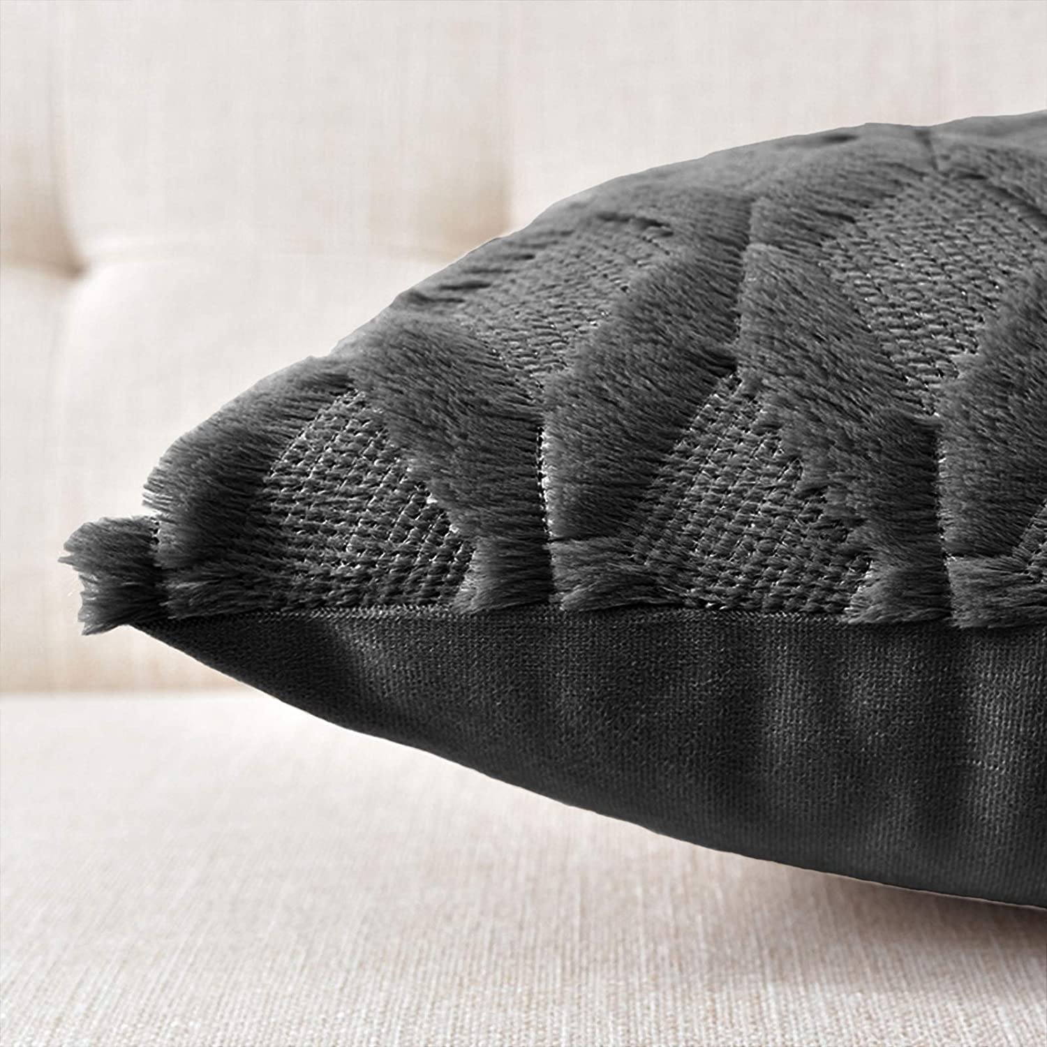 Black pillow cover with fringed tassel detailing along the edge
