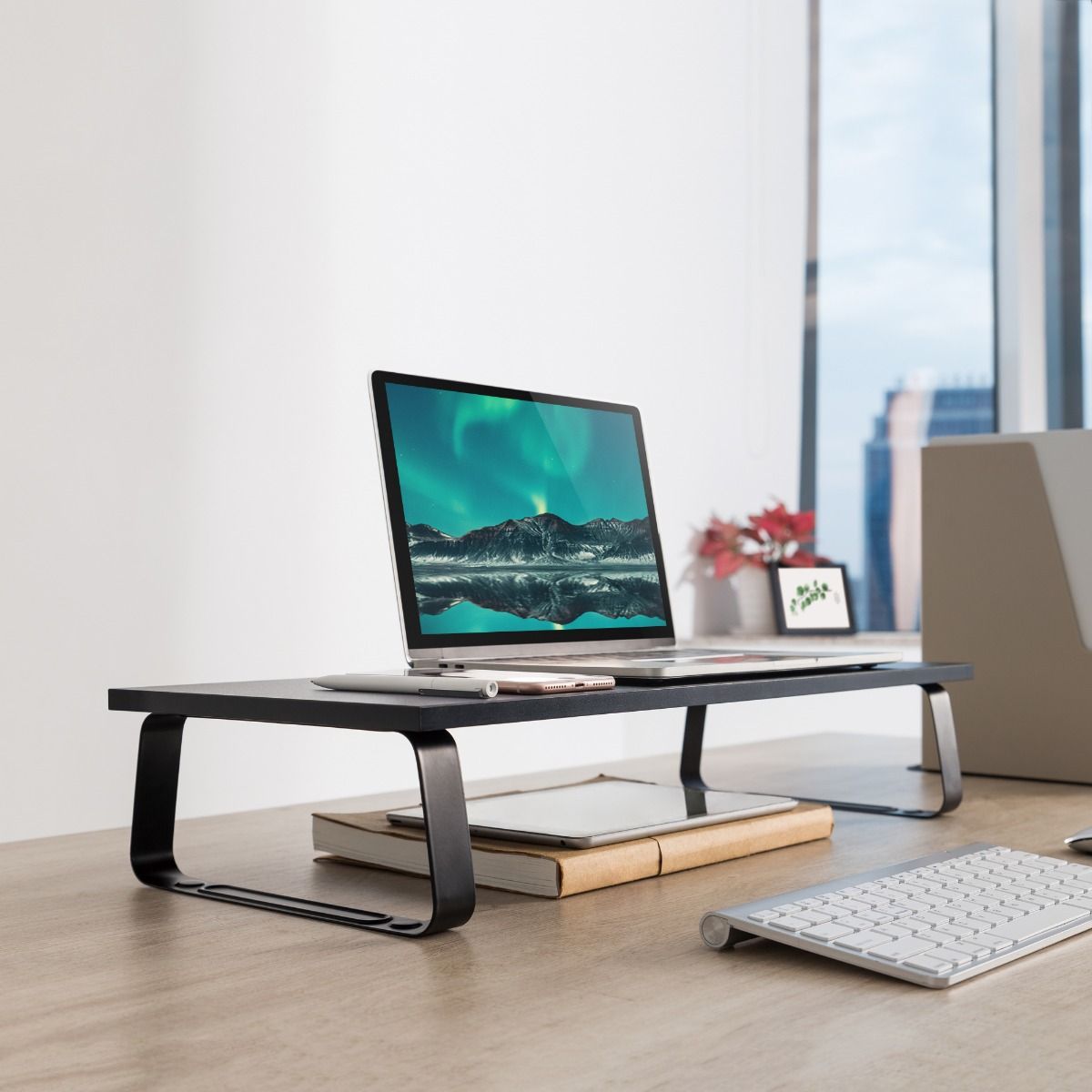 Black monitor stand riser with textured platform and open steel base on a desk