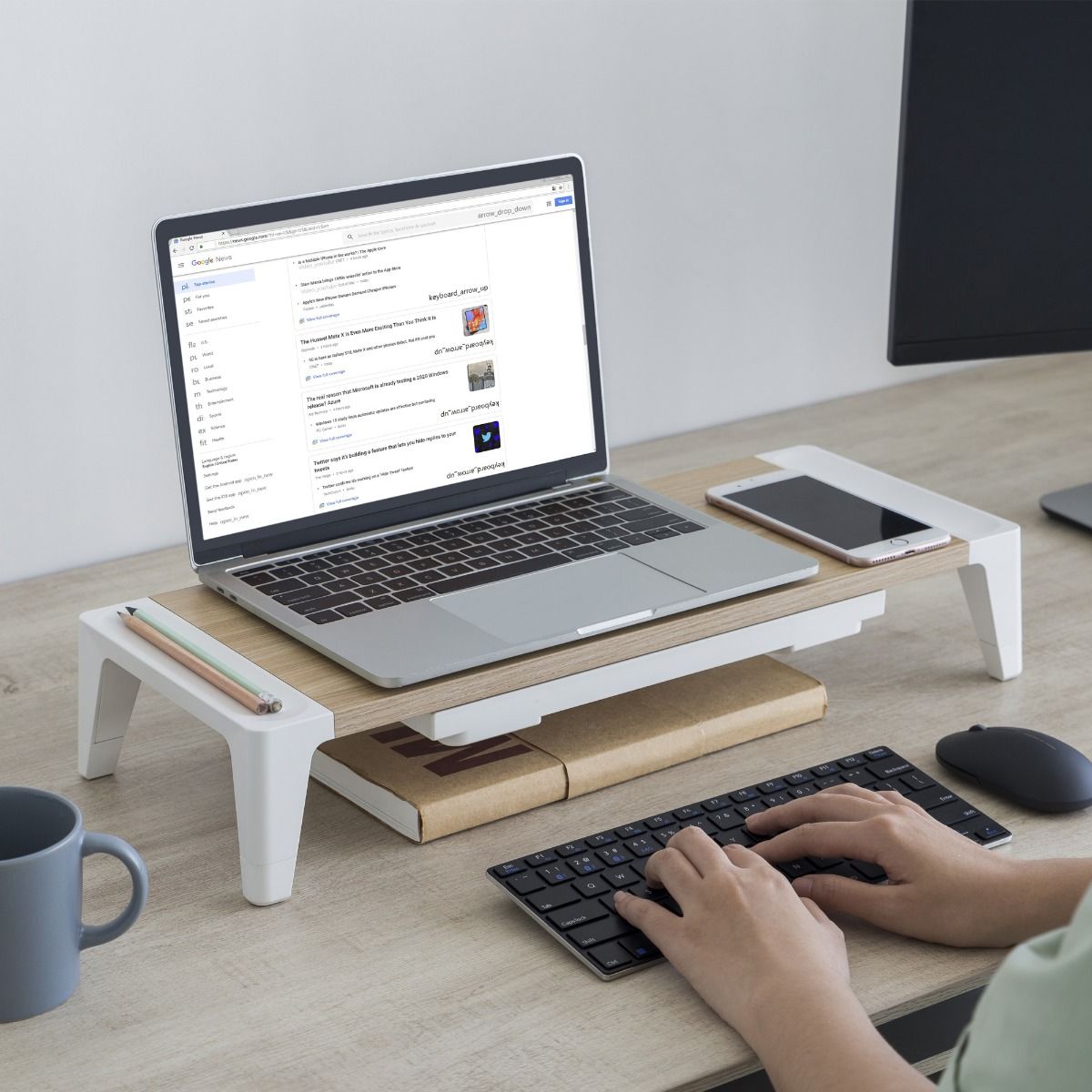 monitor stand riser with storage drawer under a laptop, light wood top and white legs