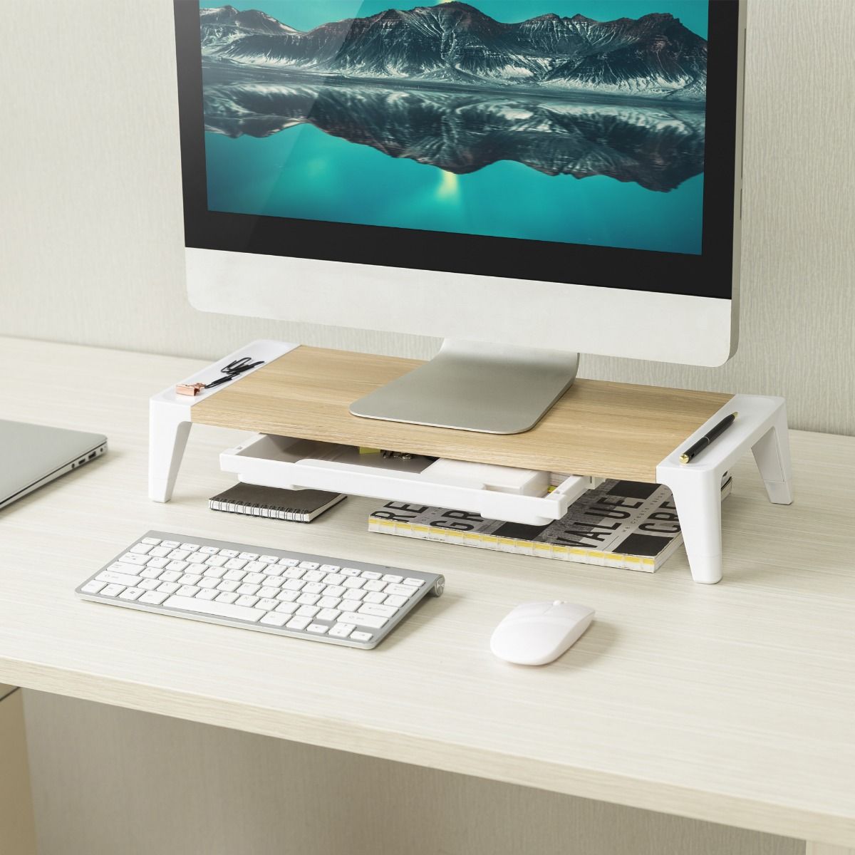 monitor stand riser with open drawer, light wood top with books and accessories