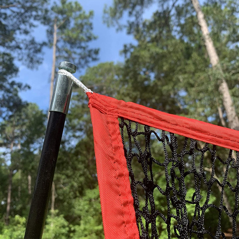 Red net fabric edge attached to a black metal pole on a golf practice net