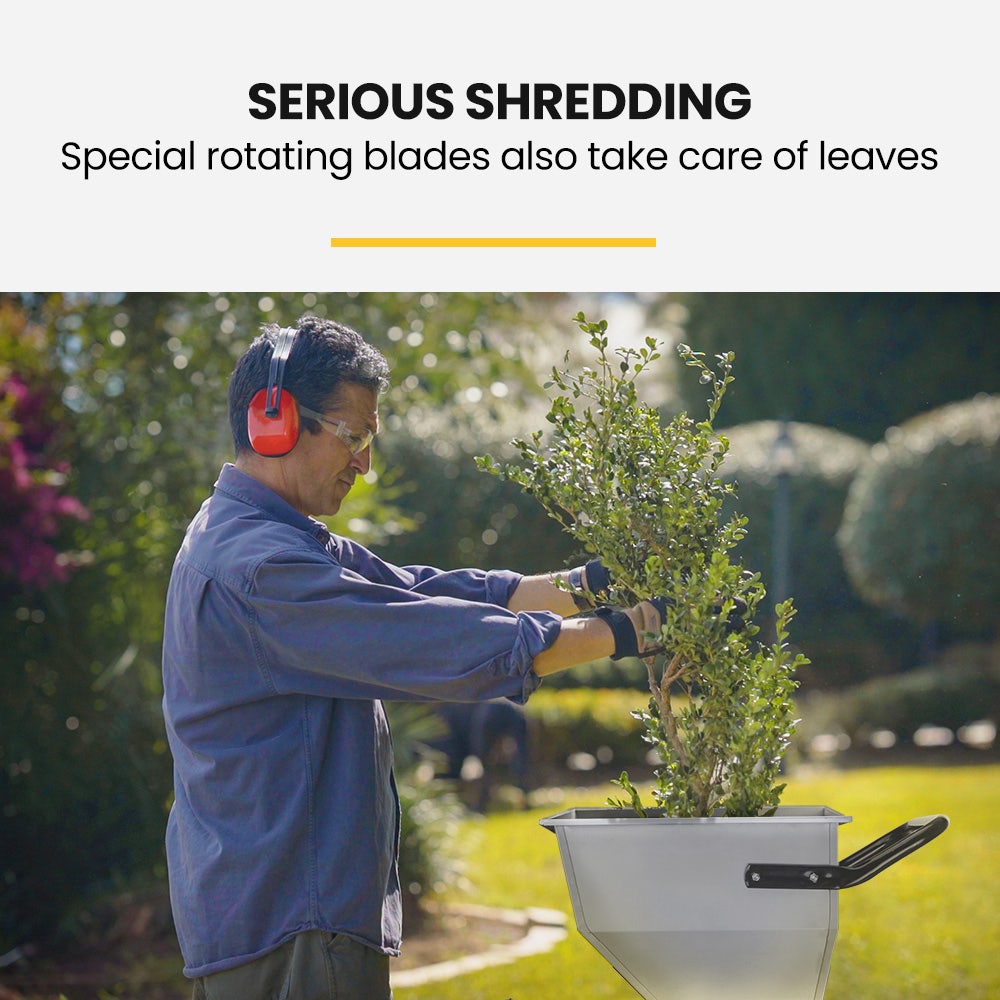 Wood chipper shredder in use: operator feeds branches into the hopper