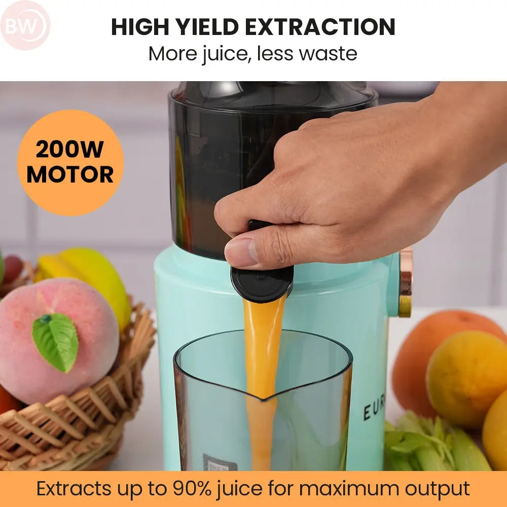 Seafoam green cold press juicer filling a glass with orange juice from spout