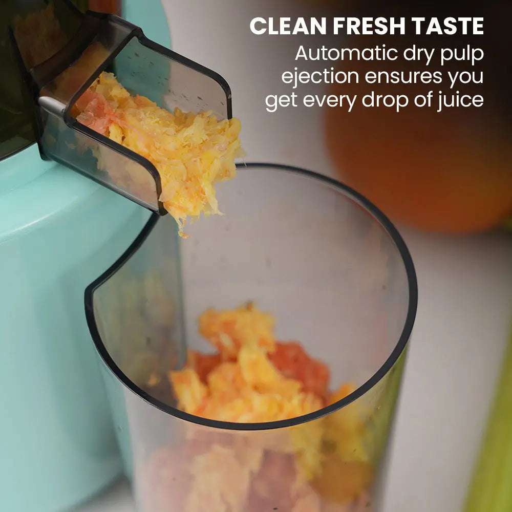 Seafoam green cold press juicer with pulp chute and stream of juice into a jug