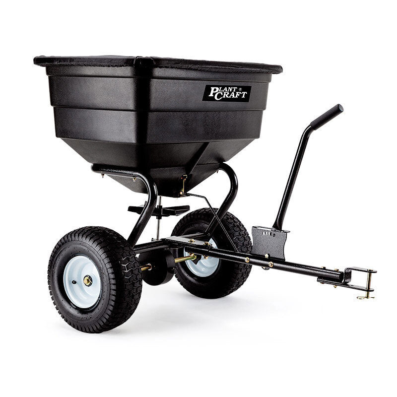 Tow-behind broadcast spreader with large black hopper, two pneumatic wheels, and hitch bar