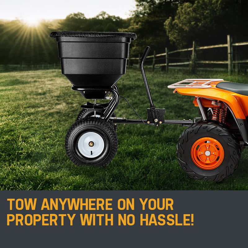 Tow-behind broadcast spreader with black hopper, large front wheel, and angled spreader chute