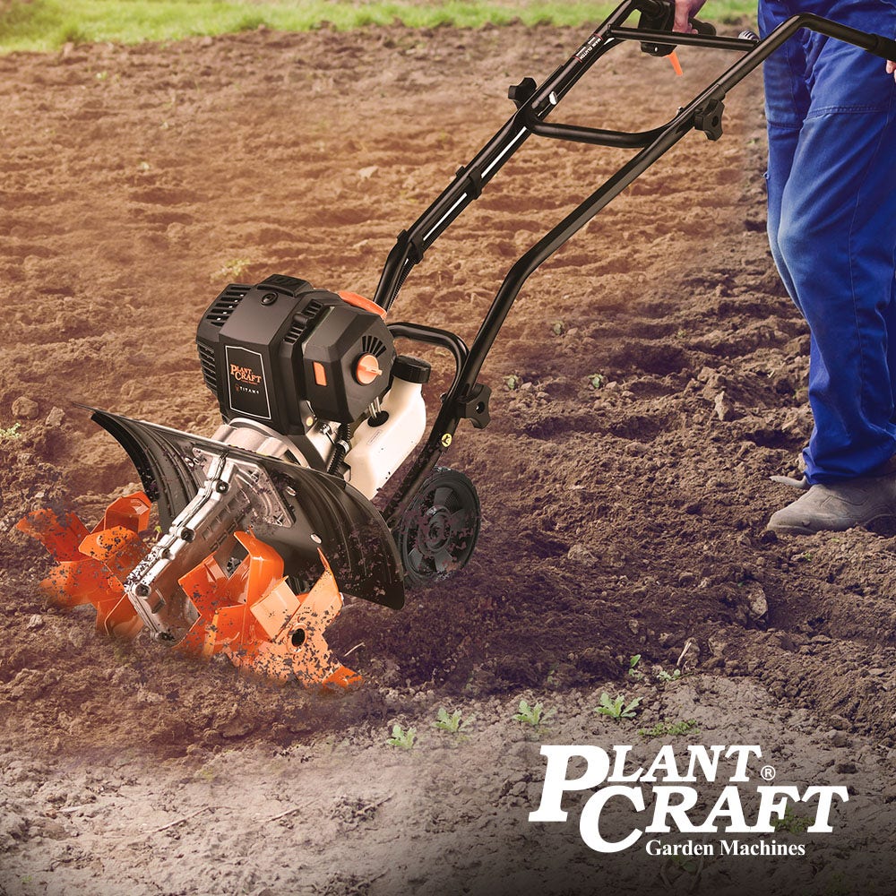 Handheld garden cultivator in use with orange tines tilling soil