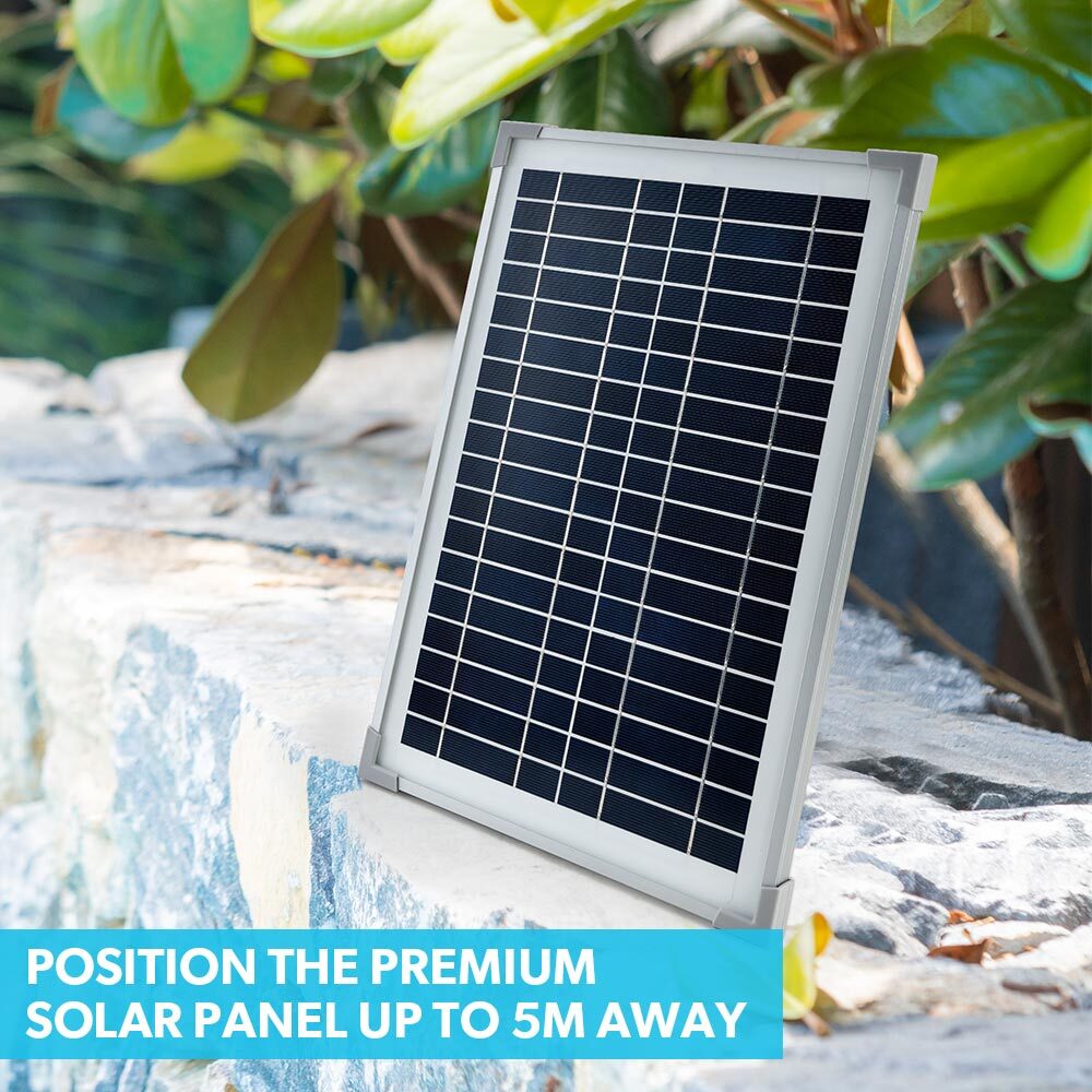 Solar panel for fountain pump with connected stake and hose, set on rocks
