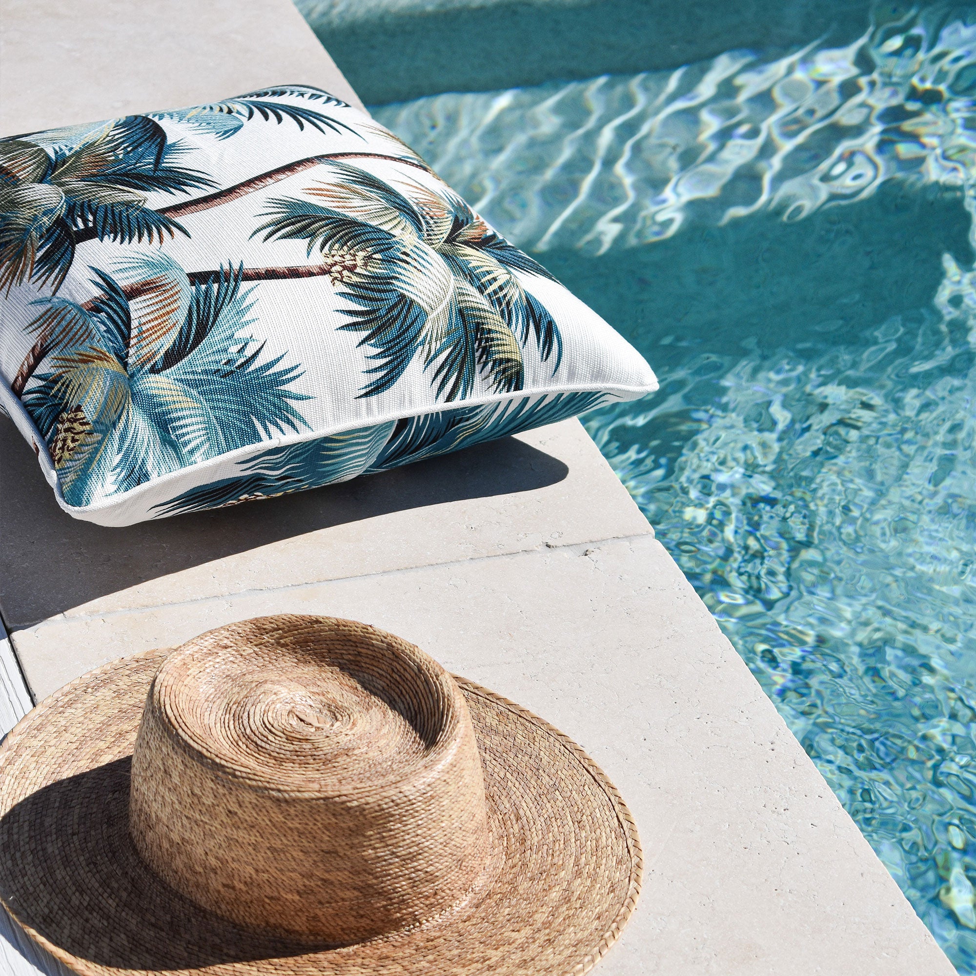 Palm tree print cushion cover with piping edge, lying on a sunbed