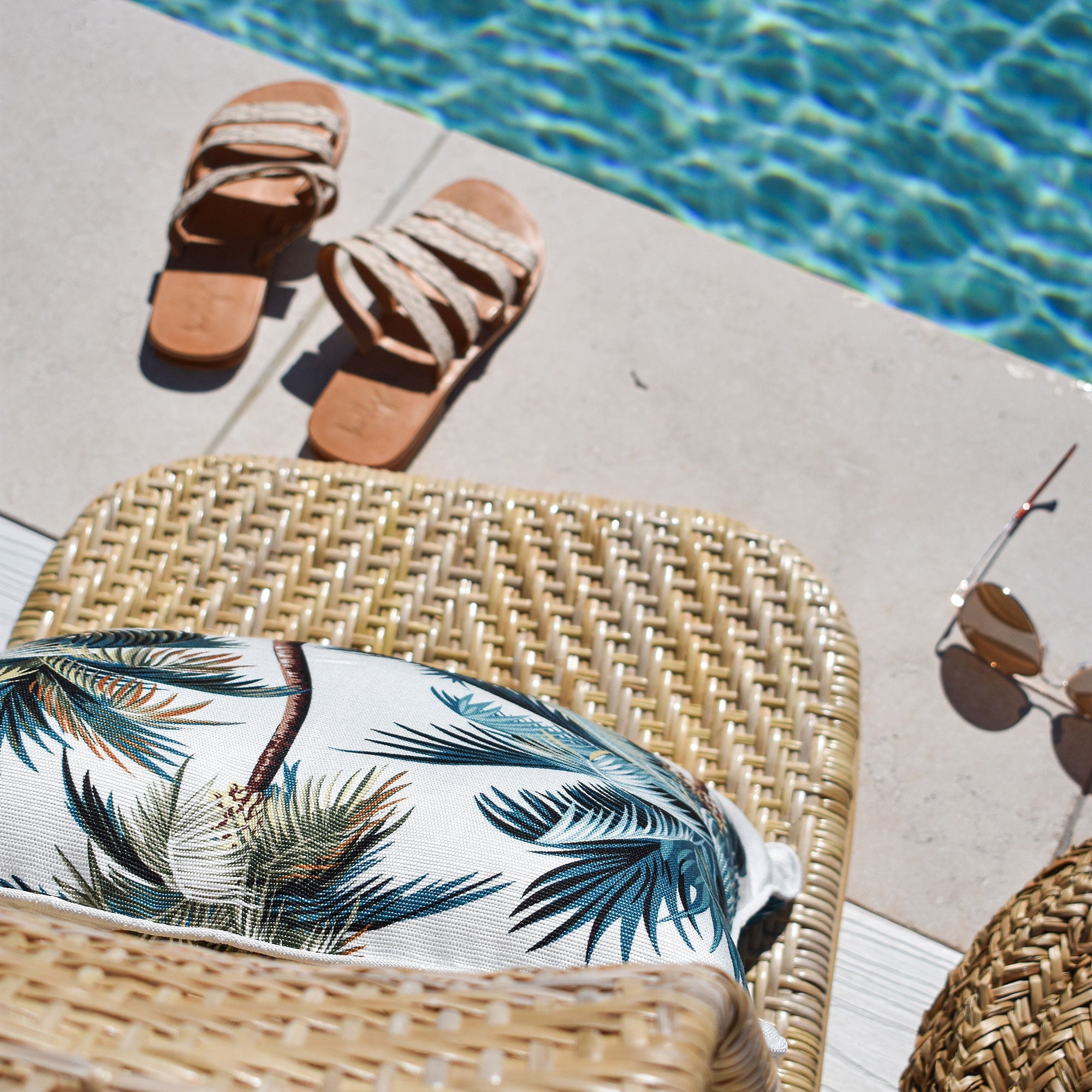 Palm tree print cushion cover with piping edge on a woven rattan chair