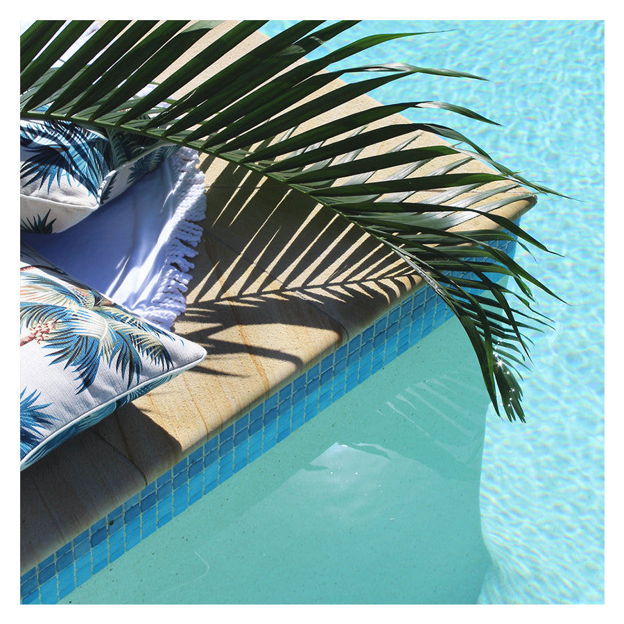 Palm leaf print cushion cover with piping edge on a poolside lounge