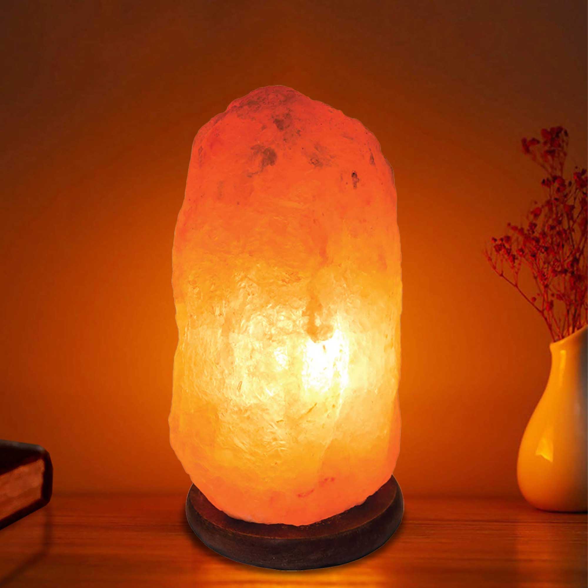 Pink Himalayan salt lamp glowing with warm light and dark base