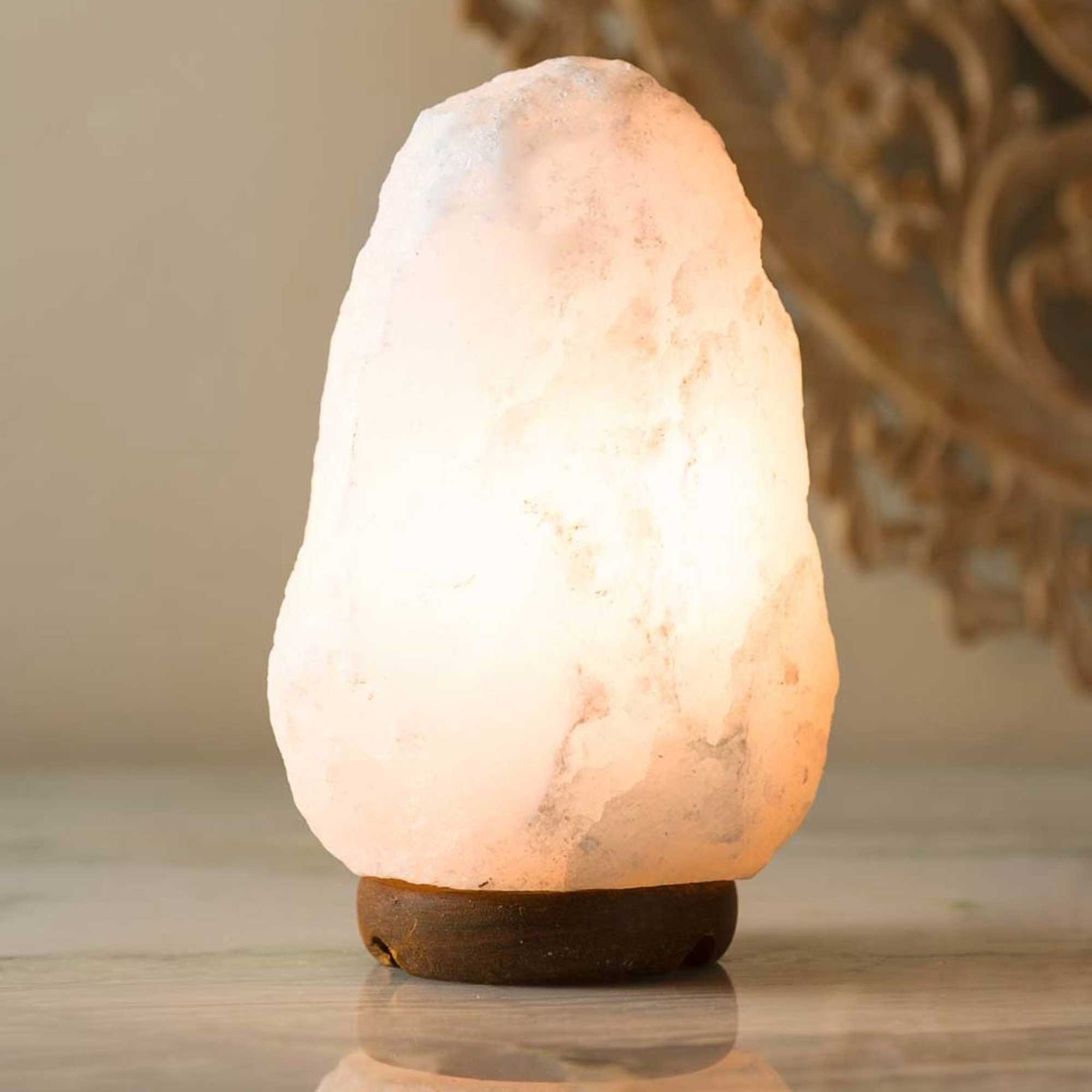Himalayan white salt lamp with warm glow, natural crystal rock shade on base.