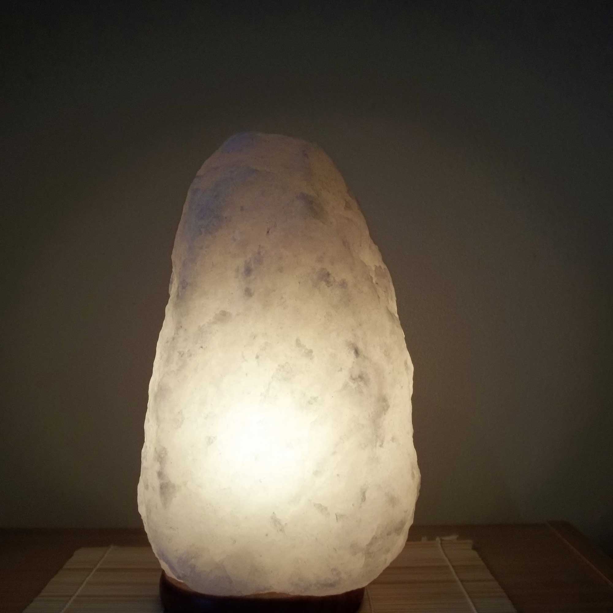Himalayan white salt lamp emitting warm light from natural crystal rock shade.