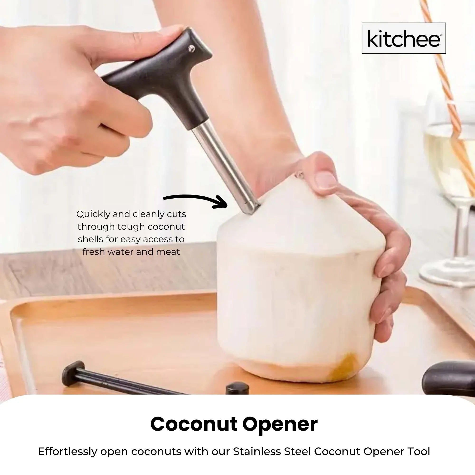 Hand using black-and-stainless coconut opener to puncture a coconut near a glass
