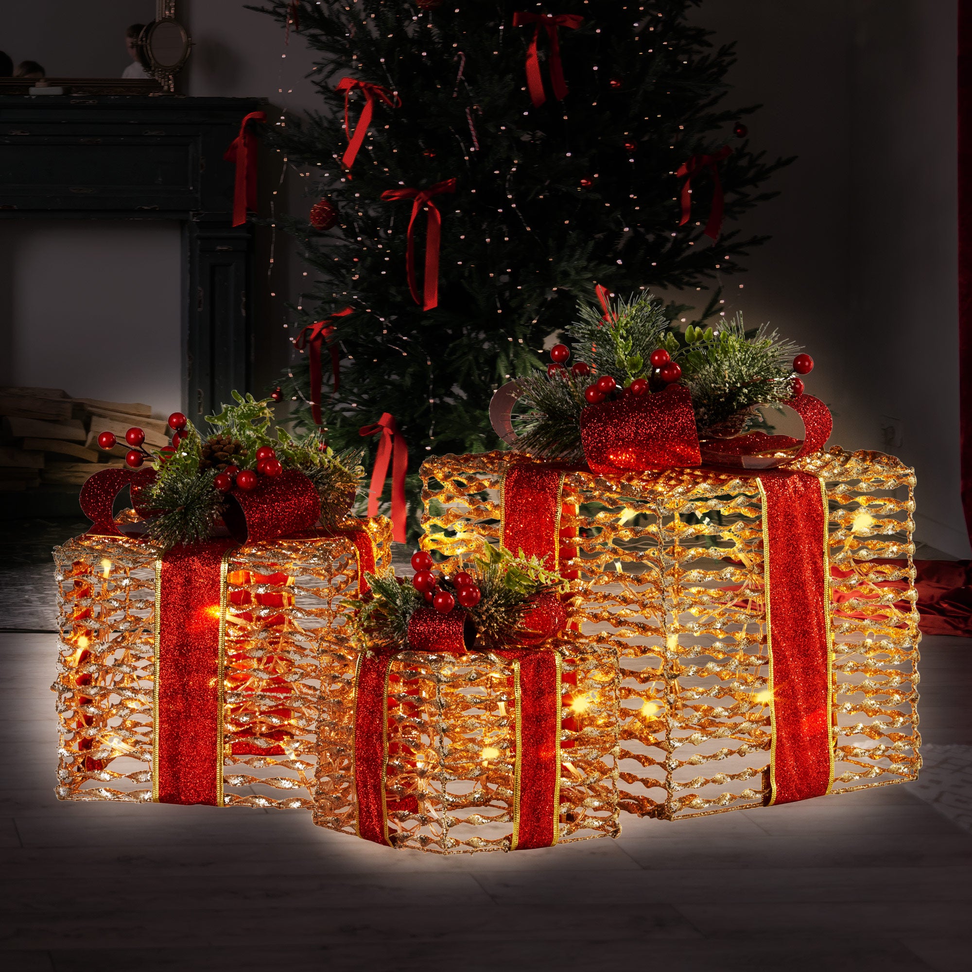 Three champagne gift boxes with red ribbon bows, pine greenery and warm LED lights