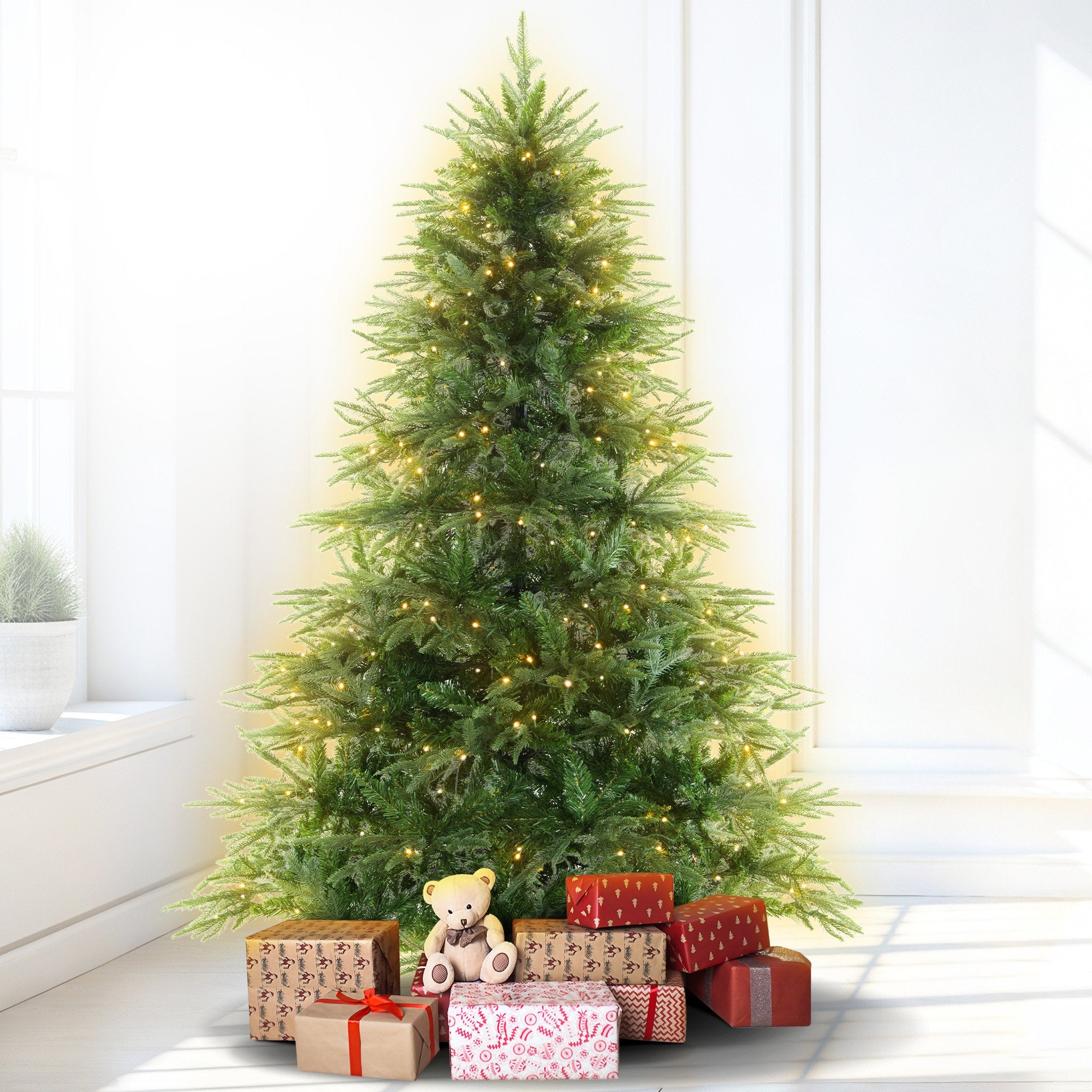 Prelit artificial fir Christmas tree with warm white LED lights, with wrapped gifts below