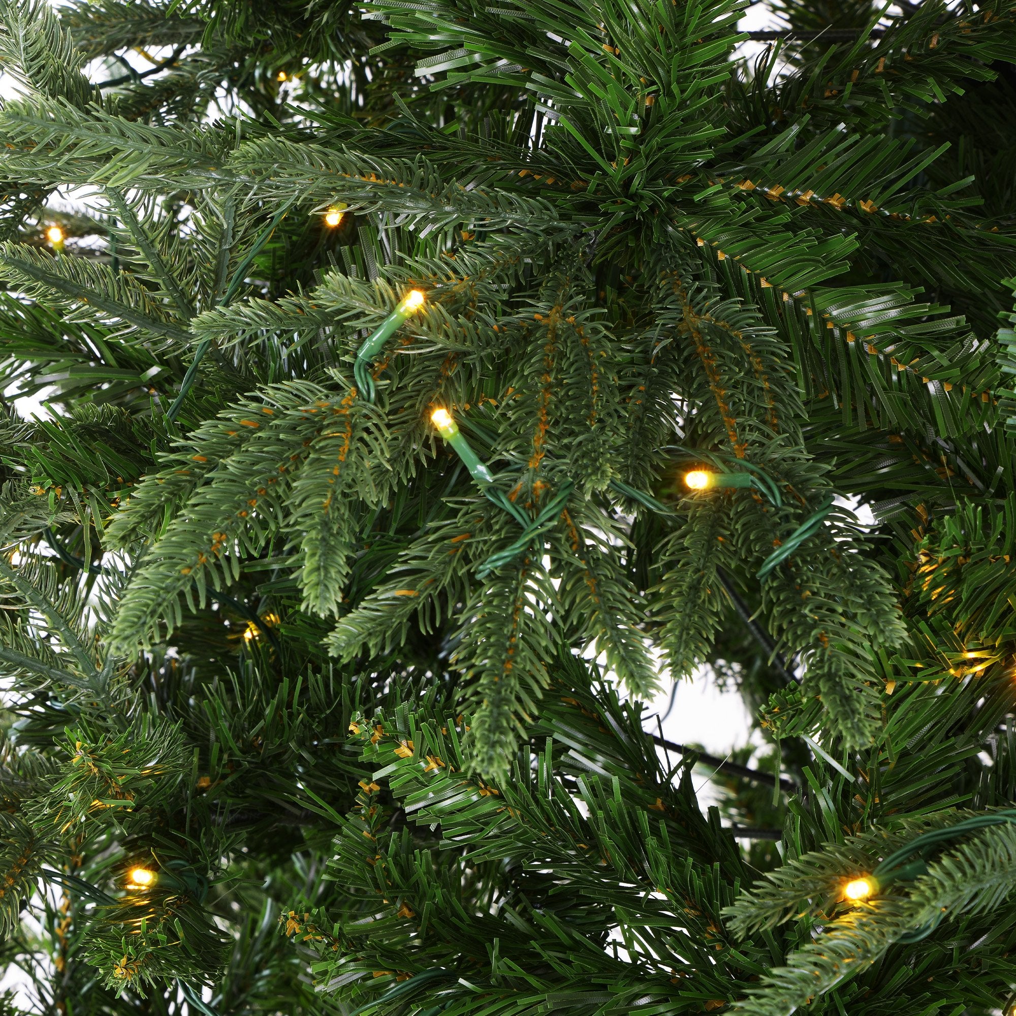 Close-up of warm LED lights on dark green Christmas tree branches