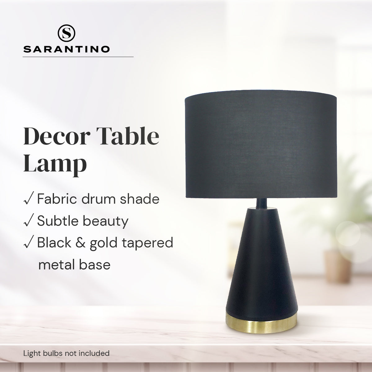 Black fabric drum table lamp with tapered metal base and gold bottom ring.