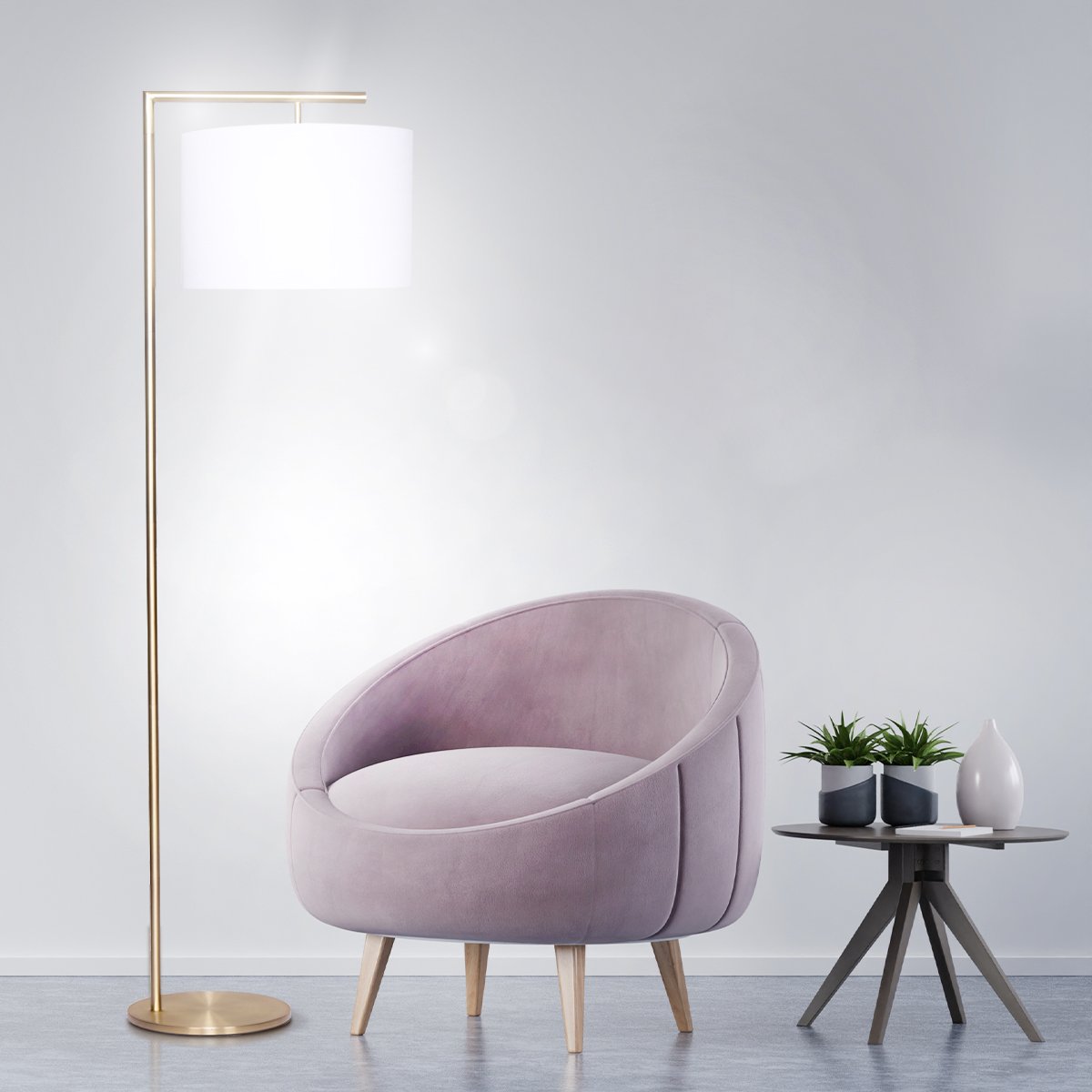 Modern arc floor lamp with white drum shade and brass base next to an upholstered chair