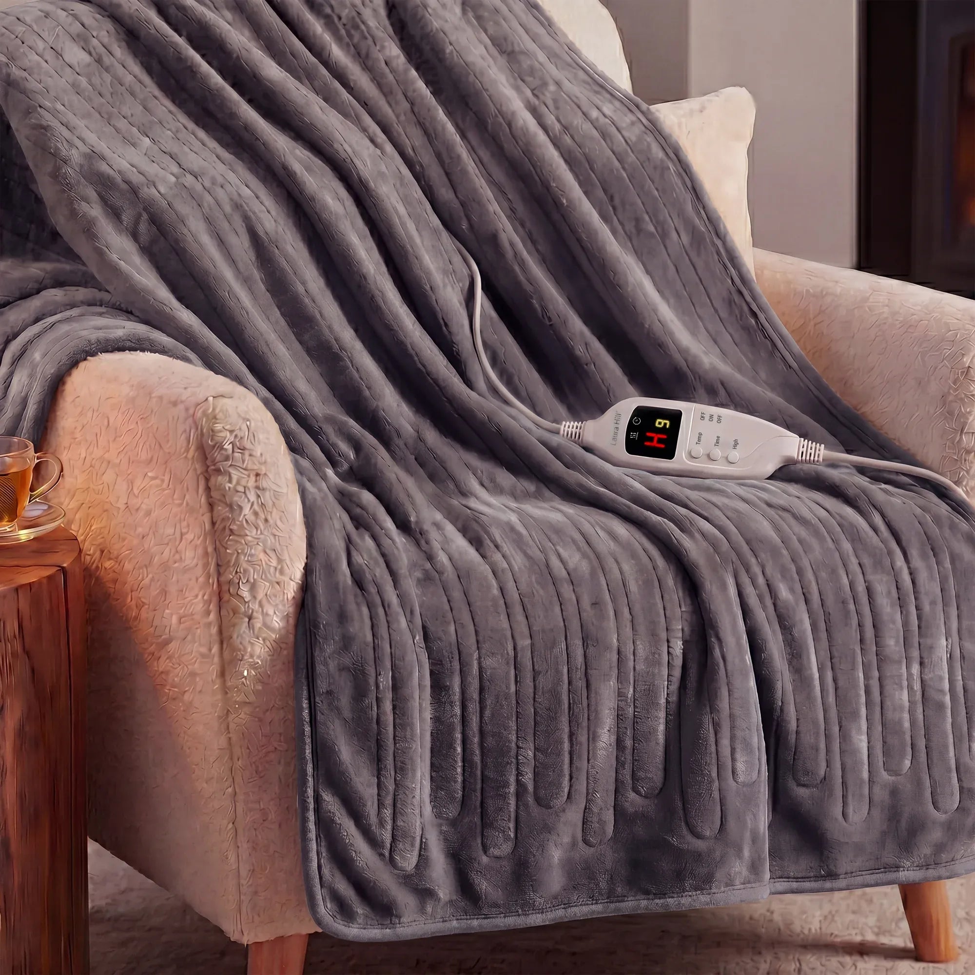 Grey heated throw blanket draped on sofa arm with controller resting on top.