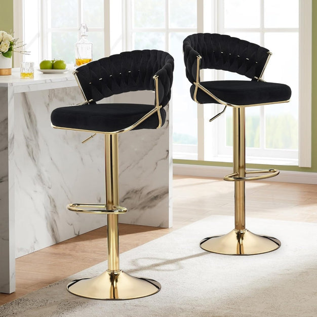 Two black velvet barstools with curved backs, padded seats, and gold pedestal bases