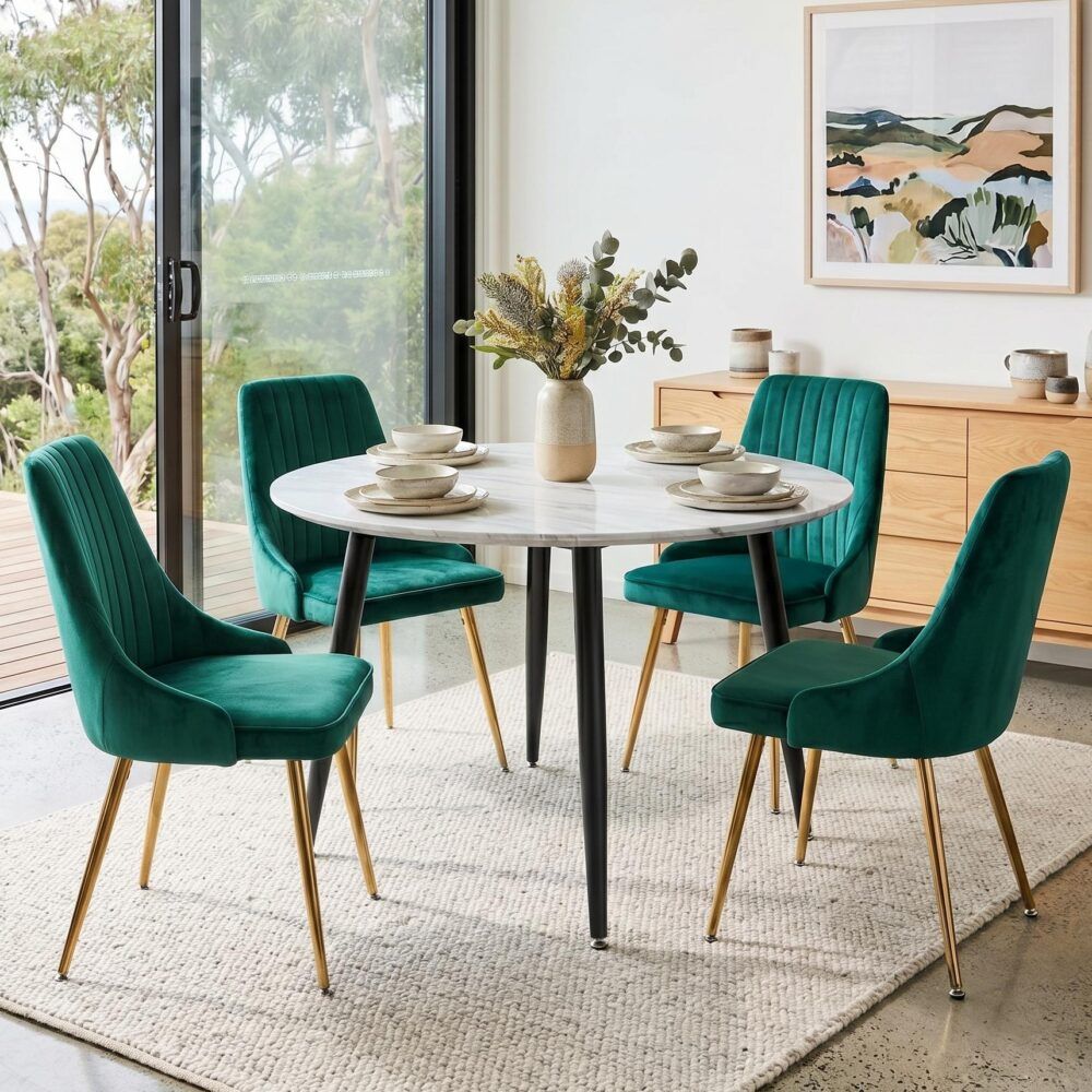 Round dining table with white top and black legs, plus 4 green velvet chairs