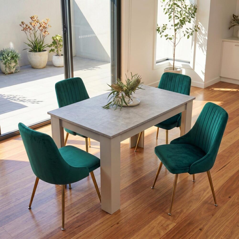 Grey rectangular dining table with four green velvet chairs in a corner layout