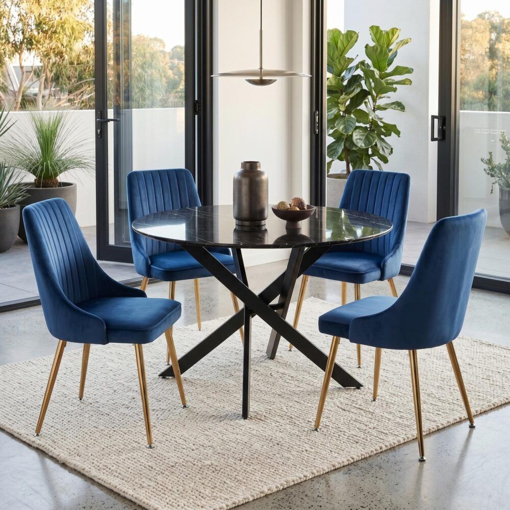 Blue velvet dining chairs with round glass table, black X base, and gold legs