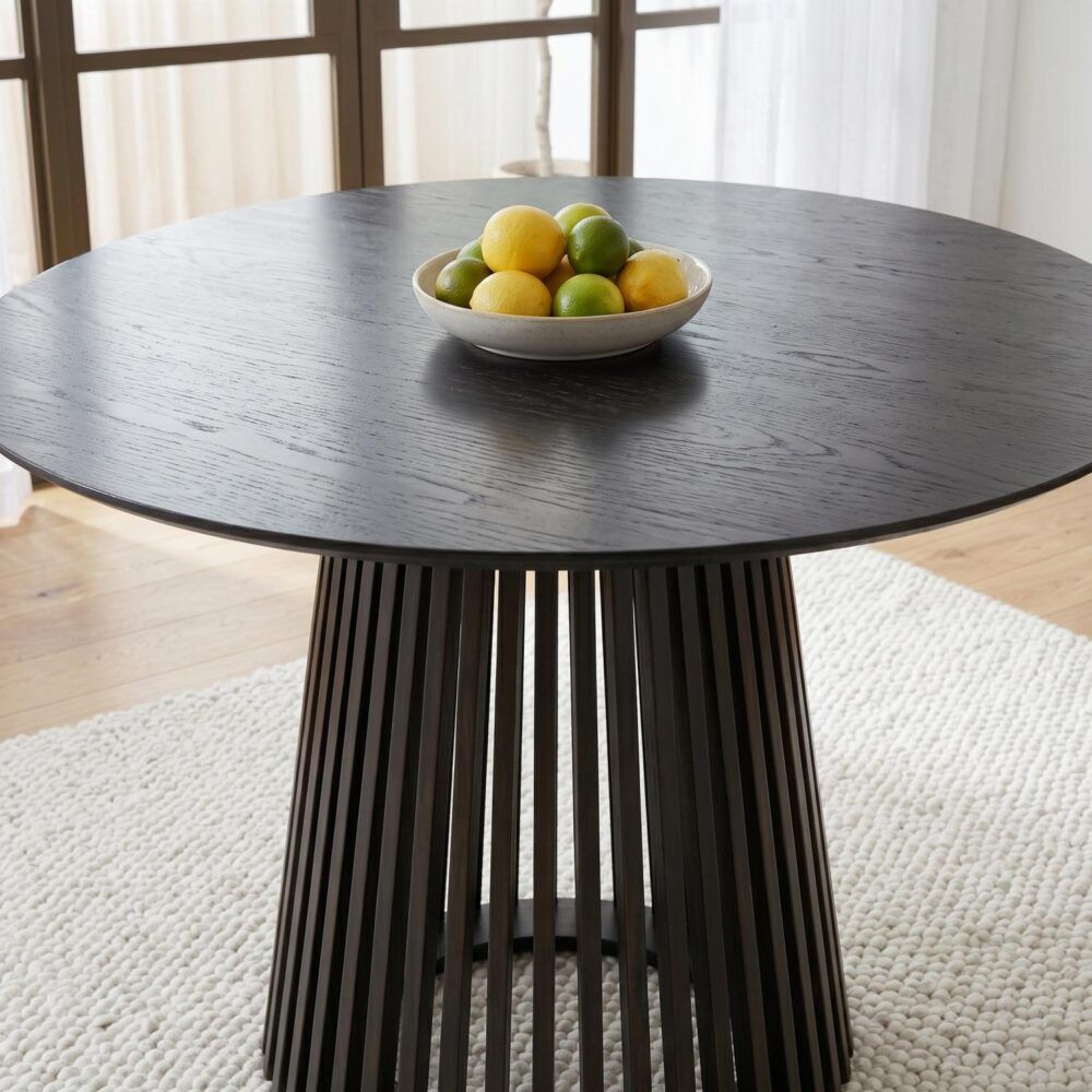 Round dark-wood dining table with ribbed black pedestal and slatted sides