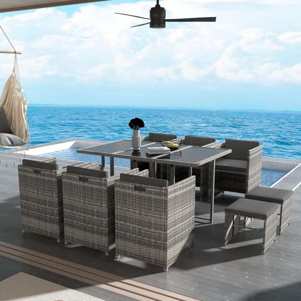 Grey outdoor dining set with glass-top table, padded seats, and woven armchairs
