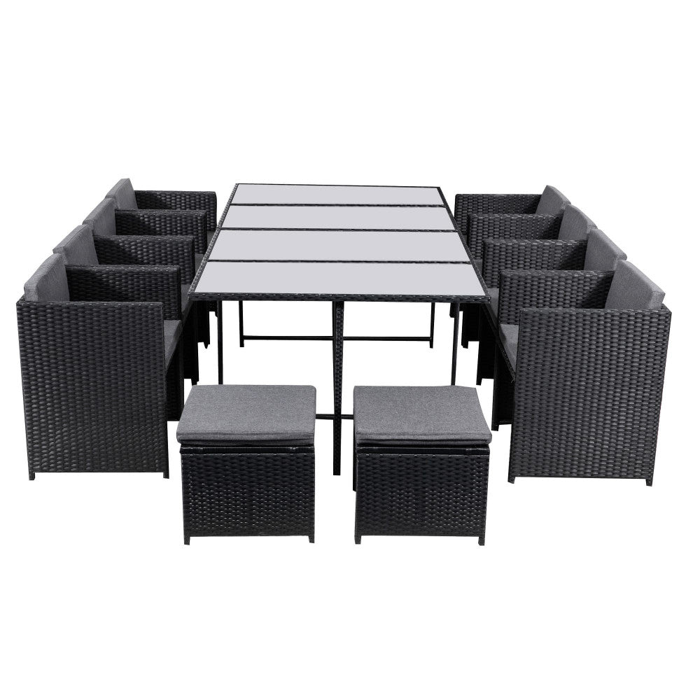 Black outdoor dining table with woven chairs and square ottomans around the tabletop
