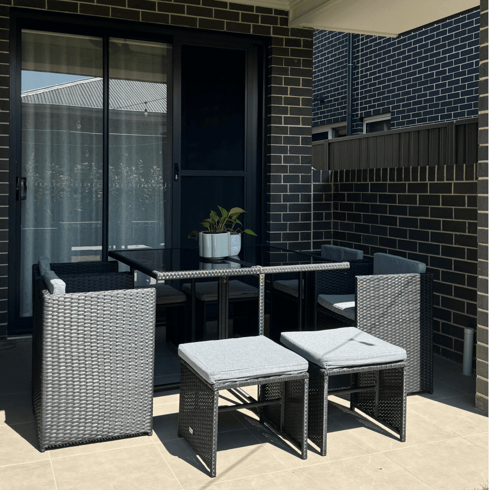 Black woven rattan dining set with rectangular table and cushioned armchairs