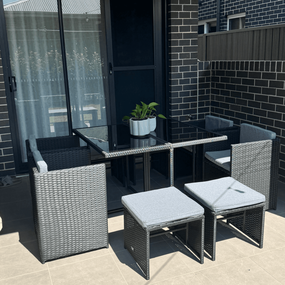 Outdoor dining set with black woven chairs and rectangular glass-top table, plus cushions