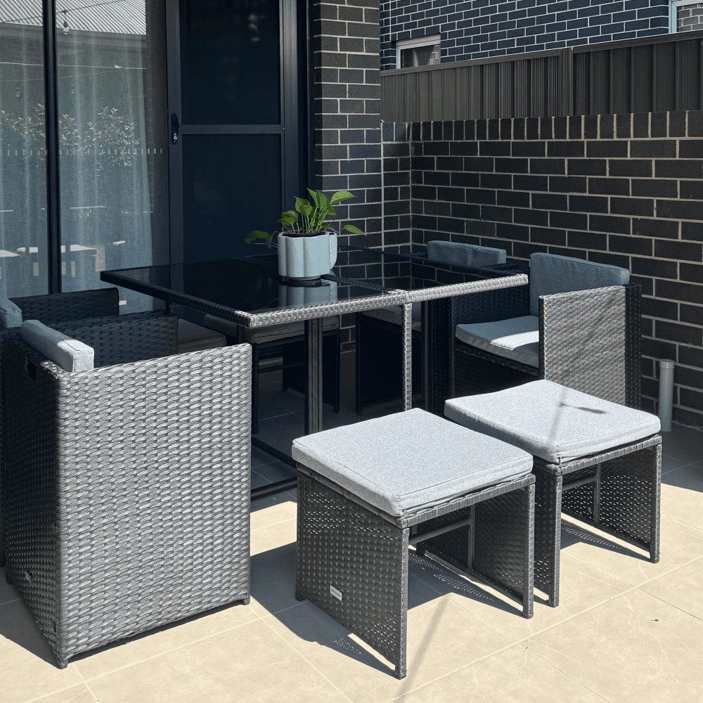 Outdoor dining set: black rectangular table with glass top and woven chairs with cushions