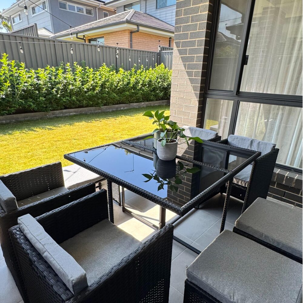 Outdoor dining set with black table and woven benches plus gray seat cushions
