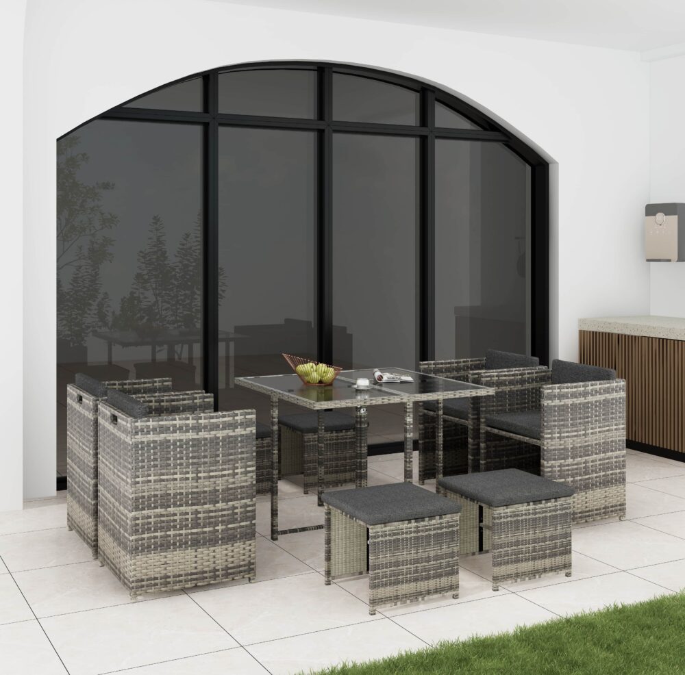 Outdoor dining set with grey woven rattan chairs, dark grey seat cushions, and glass table