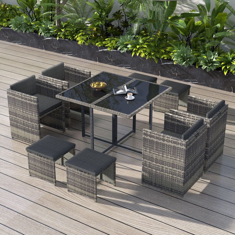 Outdoor dining set on deck: grey woven rattan chairs, ottomans, and black glass table
