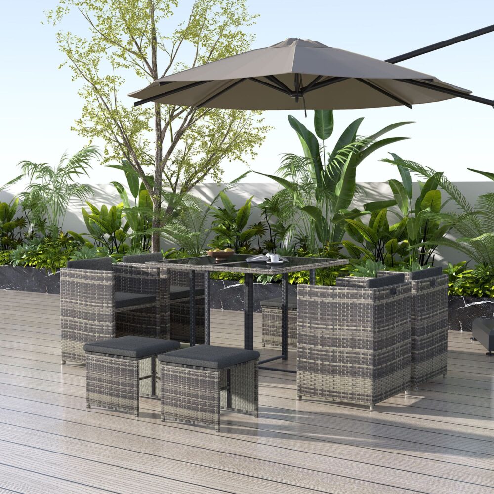 Outdoor dining set with grey woven rattan chairs, ottomans, dark grey cushions, and table