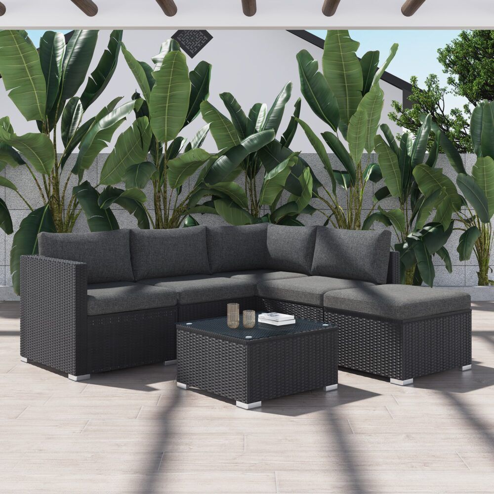 Black outdoor sectional lounge with gray cushions and glass-top ottoman coffee table