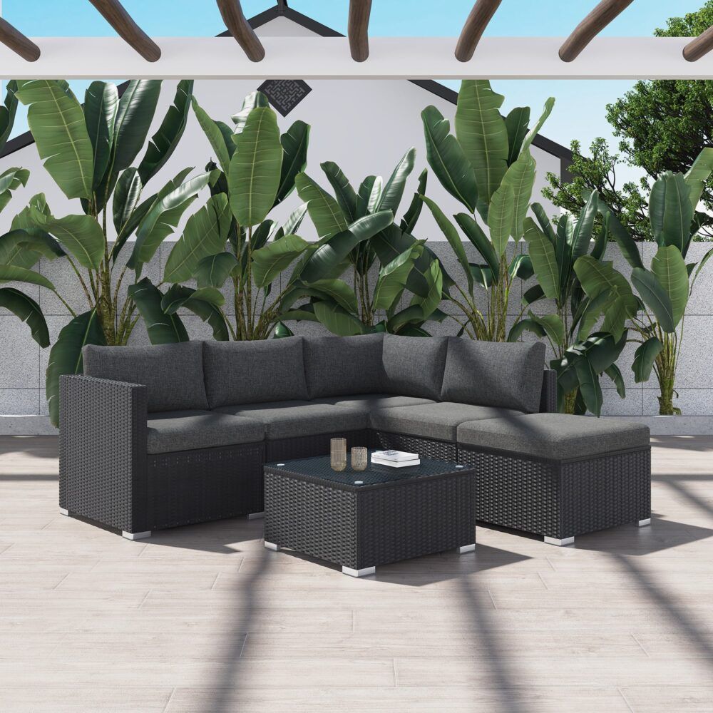 Black outdoor sectional lounge set with gray cushions and glass-top ottoman table