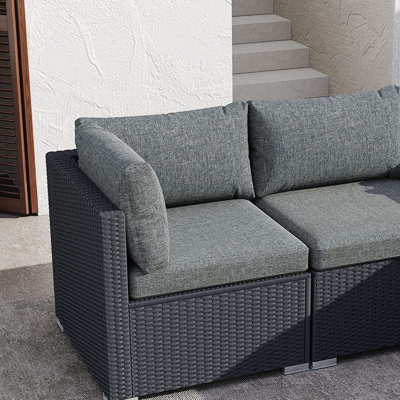 Black woven outdoor lounge armchair section with gray cushions and corner seat