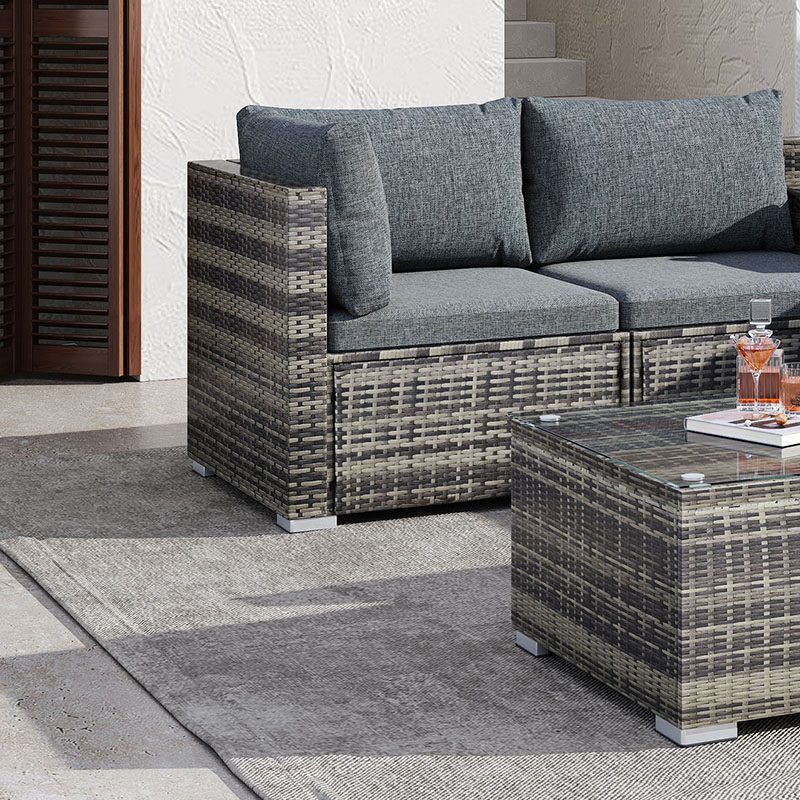 Outdoor ottoman-style corner seat with grey cushions and woven coffee table