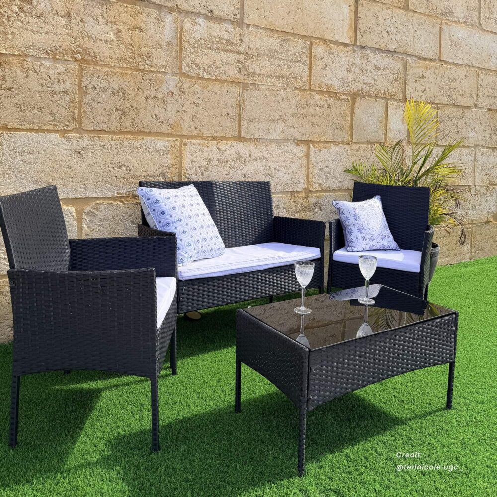 Dark wicker outdoor lounge sofa set with patterned blue cushions and glass-top table