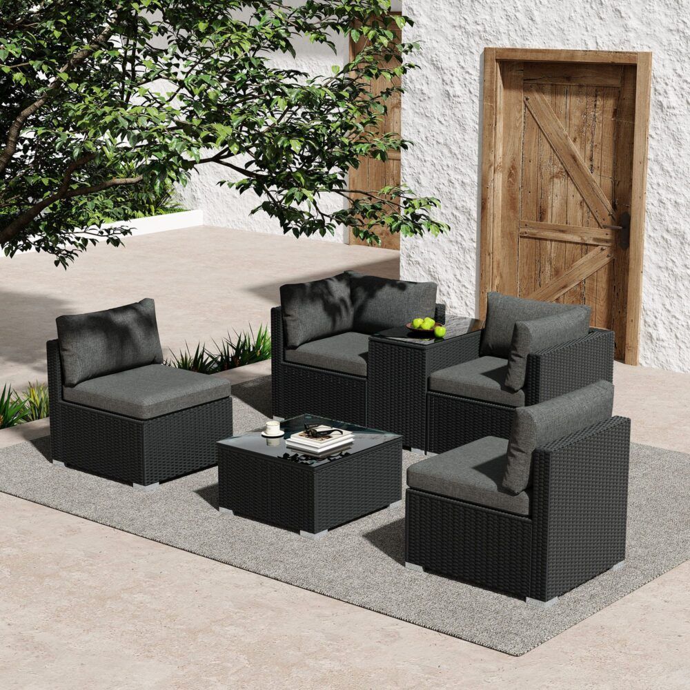 Outdoor wicker lounge set with gray cushions and dark wicker seating, arranged around a glass table