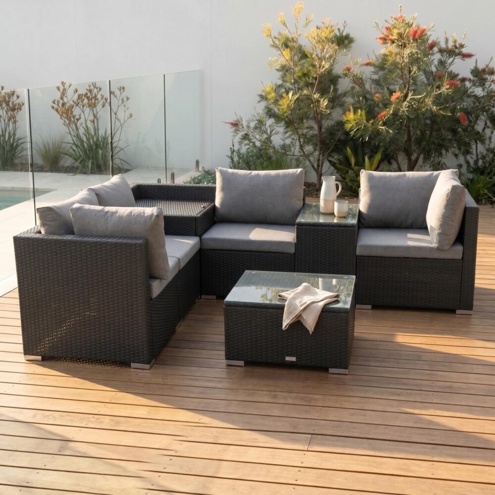 Black wicker outdoor corner sectional with grey cushions and glass-topped coffee table