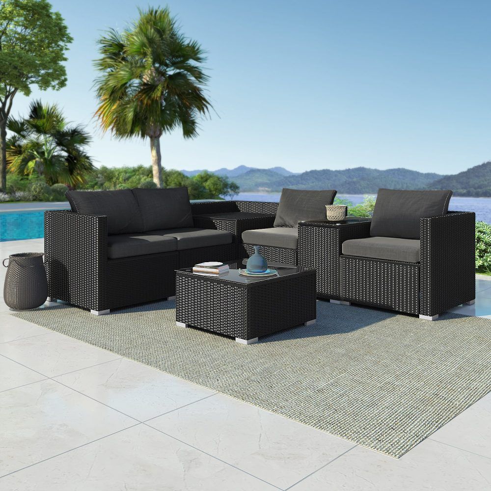 Black wicker outdoor sofa set with grey cushions, storage ottoman, and rug